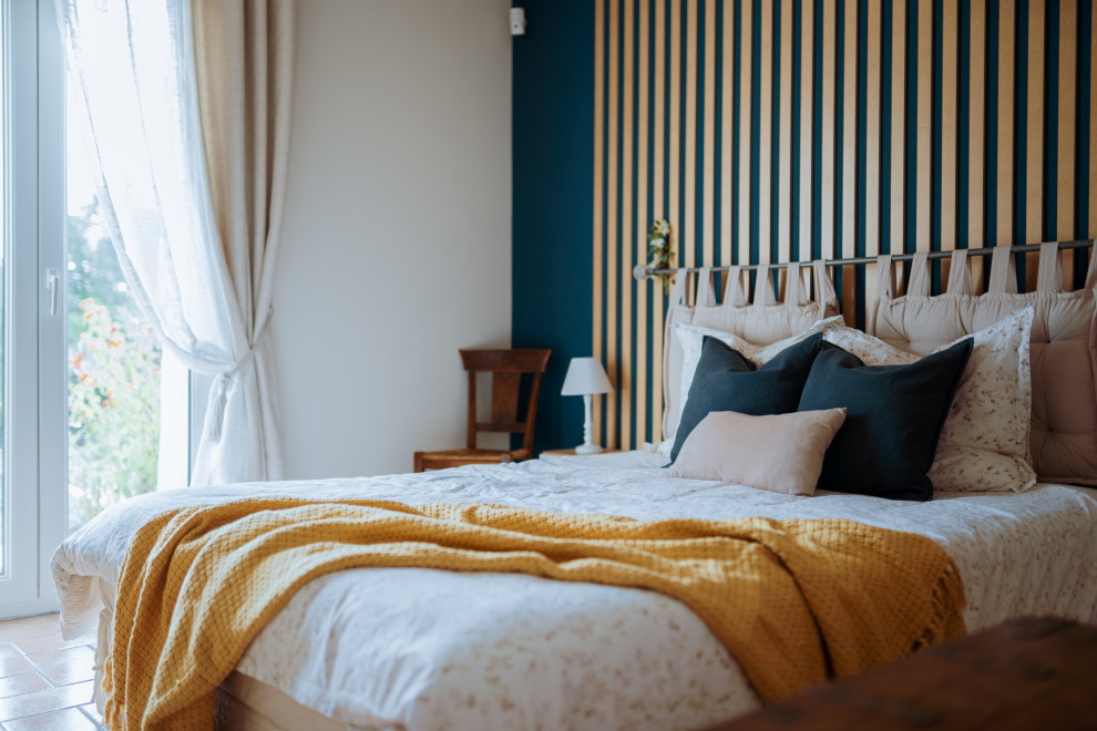 他の地域にある中くらいなカントリー風のおしゃれな主寝室 (青い壁、テラコッタタイルの床、羽目板の壁) のインテリア