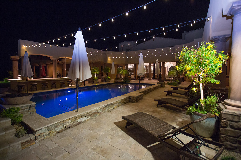 Expansive eclectic backyard rectangular pool in Phoenix with a hot tub and natural stone pavers.