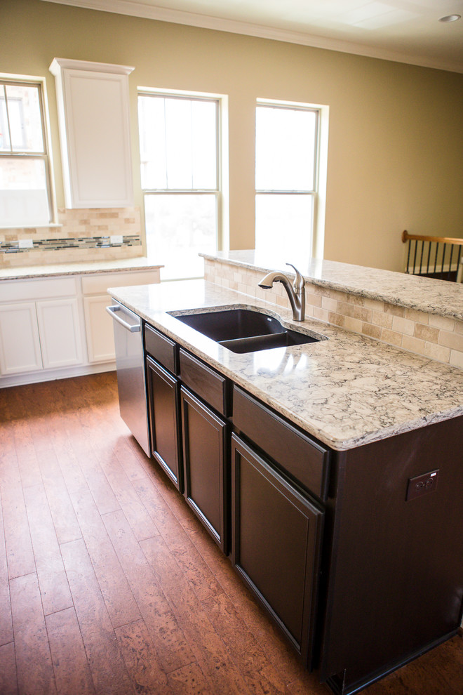 Mid-sized transitional l-shaped medium tone wood floor eat-in kitchen photo in Austin with an undermount sink, recessed-panel cabinets, white cabinets, granite countertops, beige backsplash, stone tile backsplash, stainless steel appliances and an island
