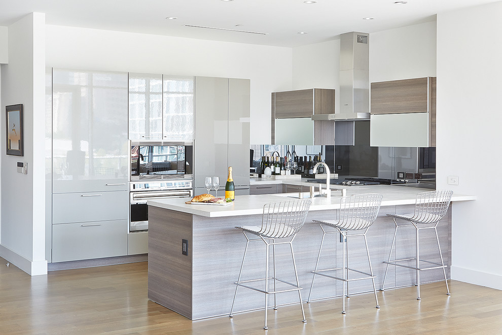 This is an example of a contemporary u-shaped kitchen in Dallas with flat-panel cabinets, grey cabinets, grey splashback, stainless steel appliances, medium hardwood floors and a peninsula.