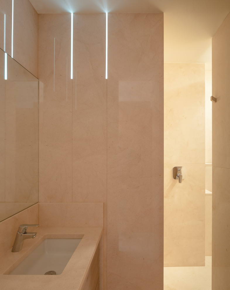 Diseño de aseo actual pequeño con armarios con paneles lisos, puertas de armario de madera oscura, sanitario de pared, baldosas y/o azulejos beige, paredes beige, lavabo bajoencimera, suelo beige y encimeras beige