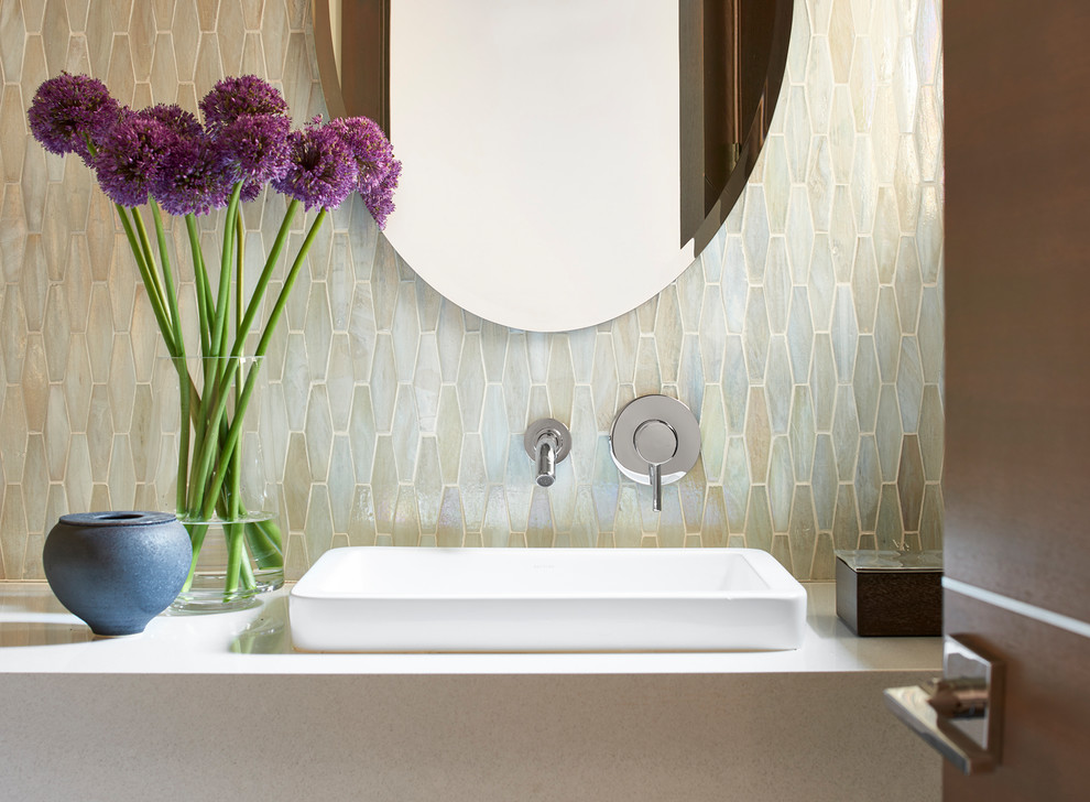 This is an example of a small modern powder room in Atlanta with a one-piece toilet, multi-coloured tile, mosaic tile, white walls, porcelain floors, a vessel sink, engineered quartz benchtops, grey floor, beige cabinets and beige benchtops.