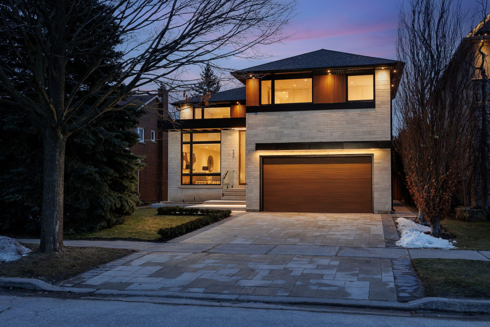Large two-storey beige house exterior in Toronto with stone veneer, a gable roof, a shingle roof and a black roof.