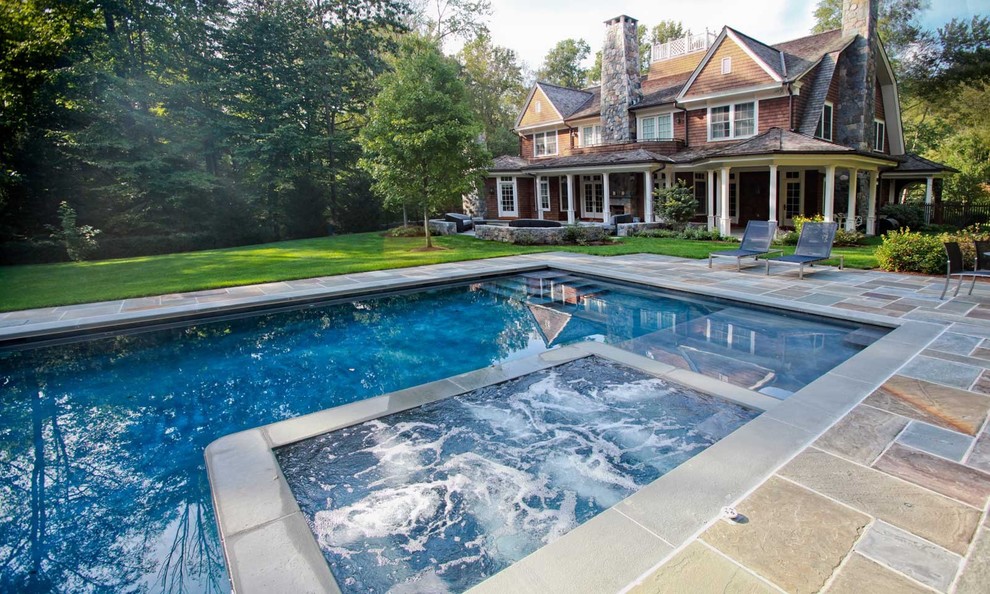 Photo of a large transitional backyard rectangular lap pool in New York with a hot tub and concrete pavers.