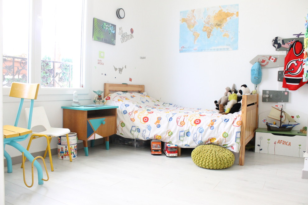 Photo of a mid-sized contemporary gender-neutral kids' bedroom for kids 4-10 years old in Paris with white walls and light hardwood floors.