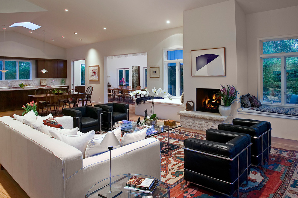 Photo of a contemporary open concept living room in Los Angeles with white walls, a hanging fireplace and a brick fireplace surround.