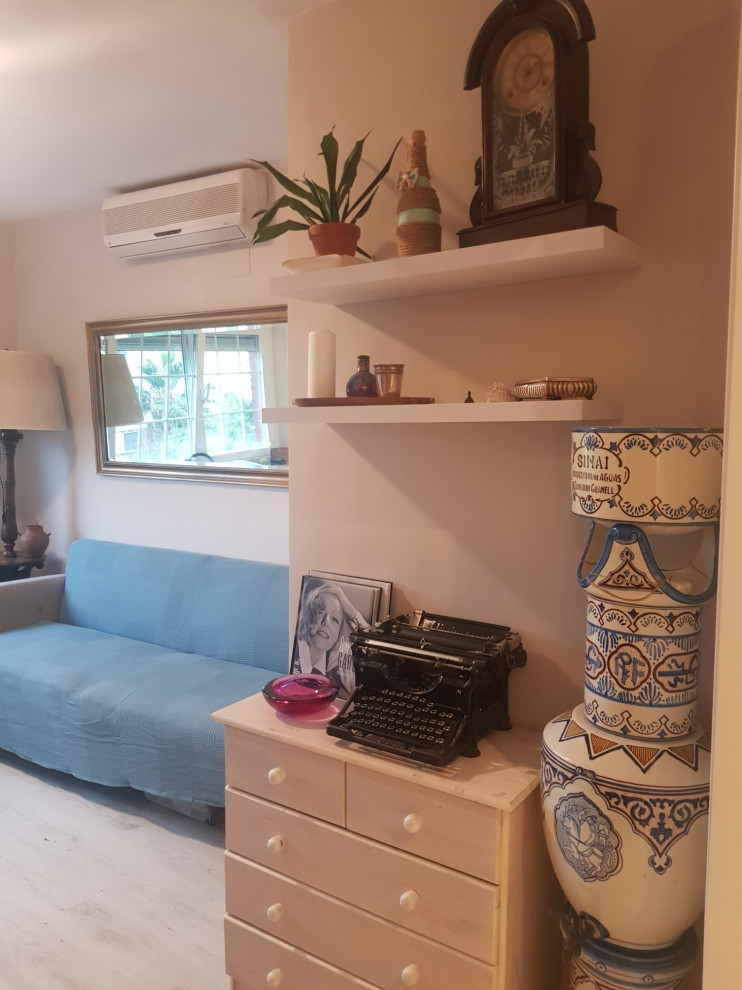 Стильный дизайн: маленькая гостиная комната в стиле ретро с бежевыми стенами, полом из ламината, телевизором на стене и белым полом для на участке и в саду - последний тренд