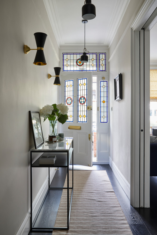 Photo of a contemporary entryway in London with dark hardwood floors, white walls, a single front door, a white front door and black floor.