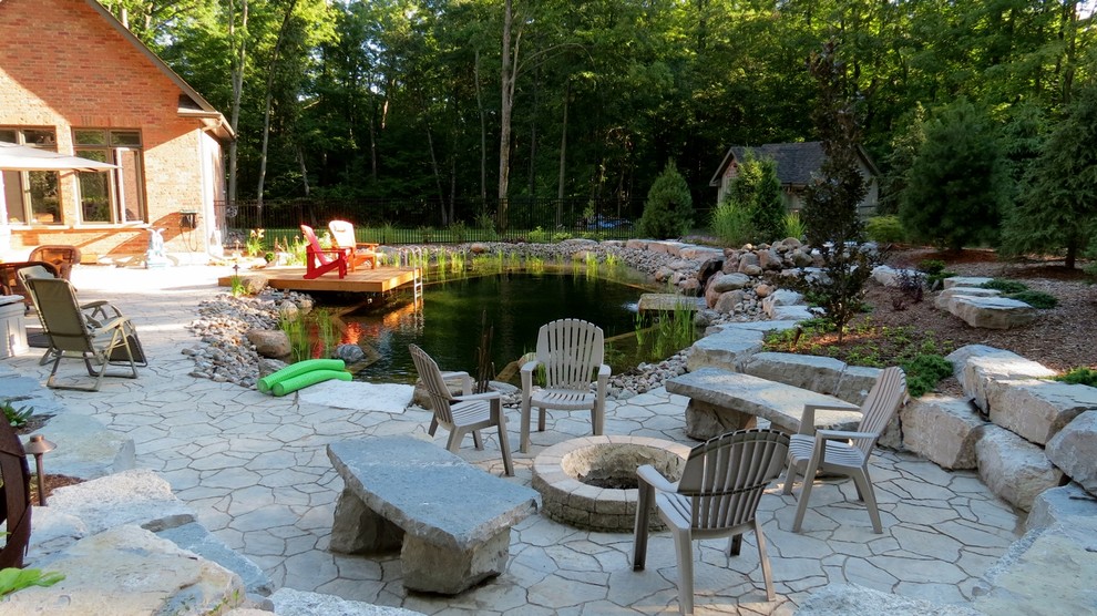 Large traditional backyard custom-shaped natural pool in Toronto with a water feature and natural stone pavers.