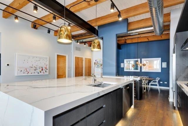 Large transitional galley medium tone wood floor and brown floor eat-in kitchen photo in Chicago with an undermount sink, flat-panel cabinets, black cabinets, marble countertops, white backsplash, marble backsplash, stainless steel appliances and an island
