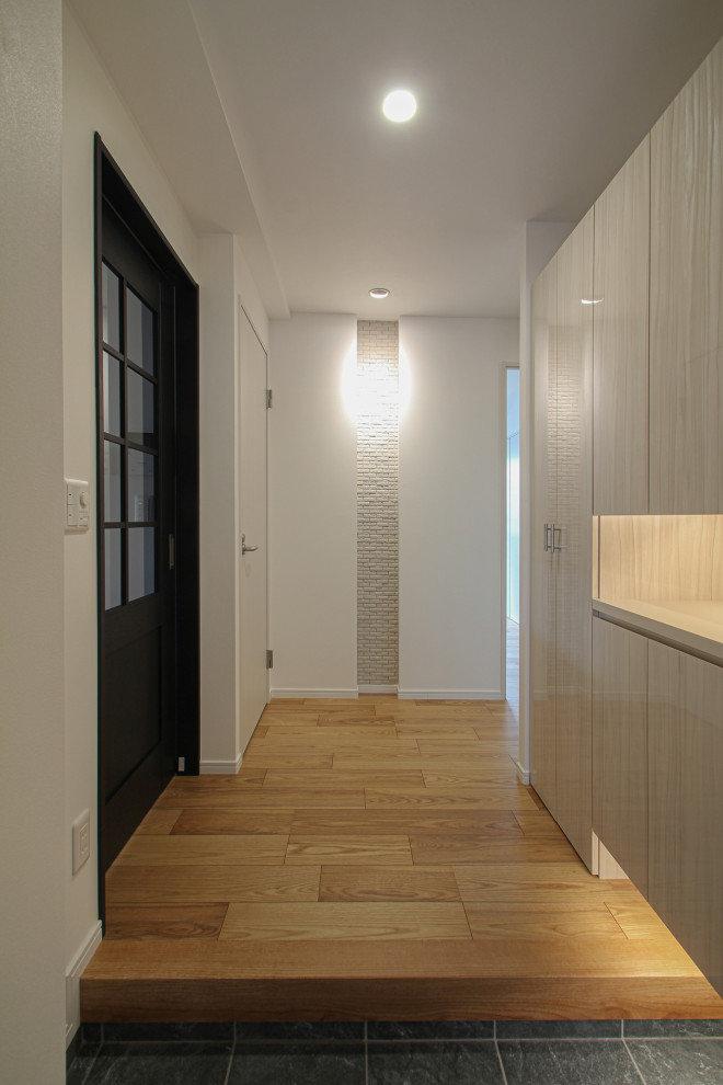 Стильный дизайн: узкая прихожая среднего размера в скандинавском стиле с белыми стенами, полом из керамической плитки, одностворчатой входной дверью, серой входной дверью, черным полом, потолком с обоями и обоями на стенах - последний тренд