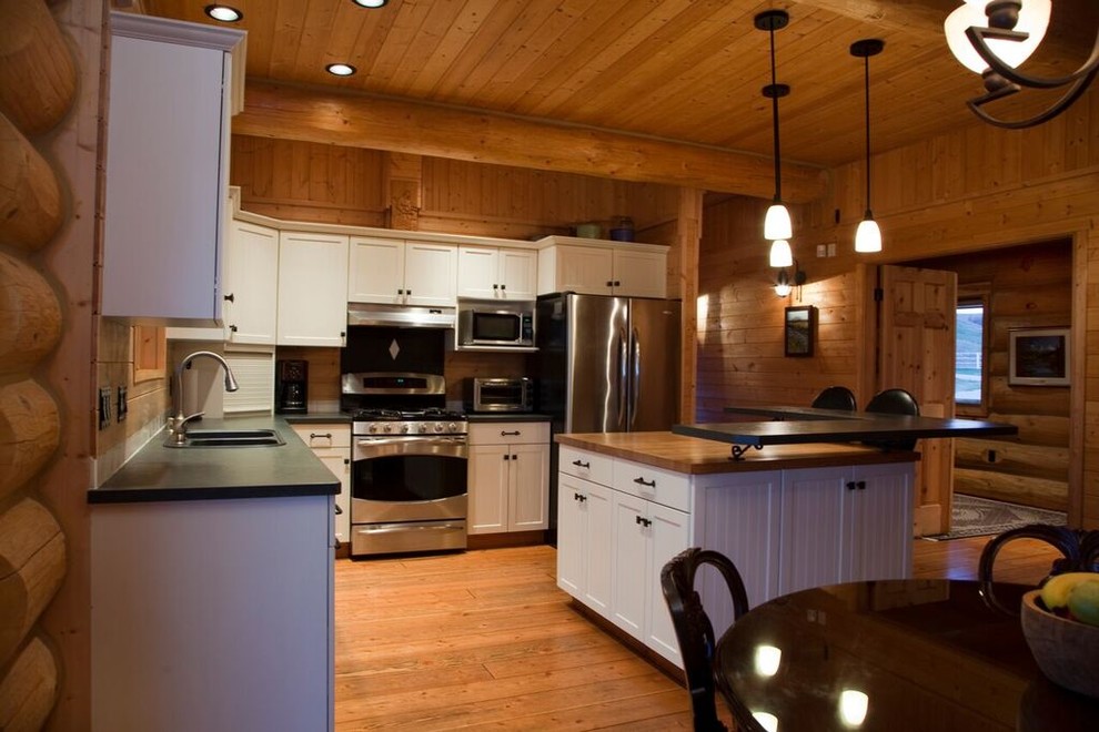 Example of a mid-sized mountain style l-shaped medium tone wood floor kitchen design with shaker cabinets, stainless steel appliances and an island