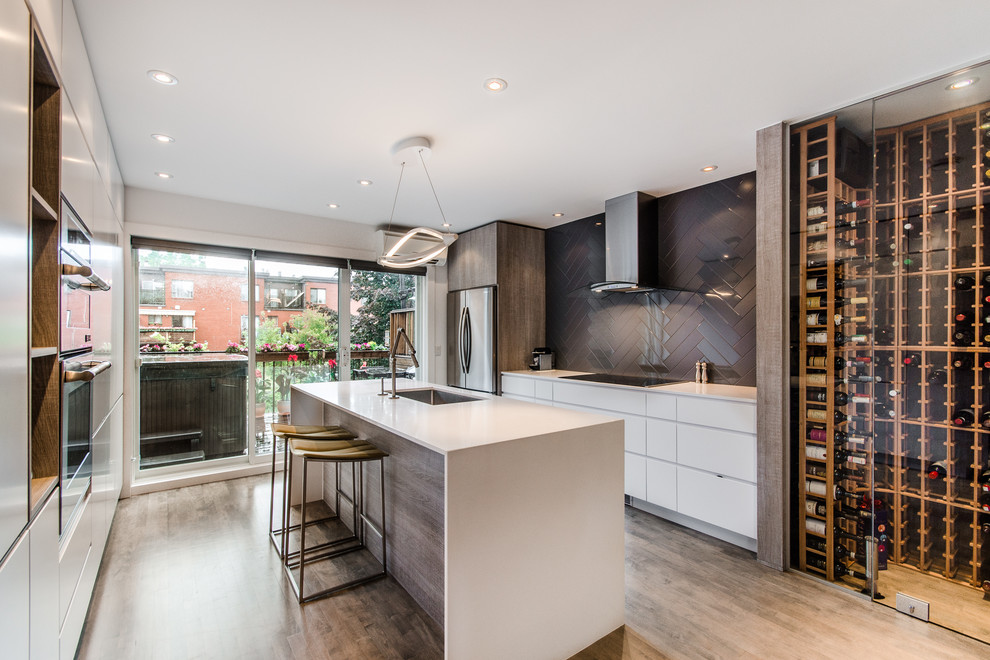 Design ideas for a contemporary galley kitchen in Montreal with flat-panel cabinets, white cabinets, grey splashback, stainless steel appliances and with island.