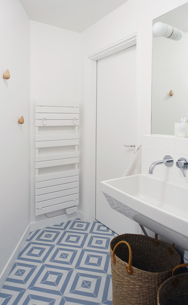 Photo of a small contemporary kids bathroom in Le Havre with beaded inset cabinets, white cabinets, an alcove shower, a one-piece toilet, white tile, ceramic tile, white walls, ceramic floors, a wall-mount sink, blue floor and a hinged shower door.
