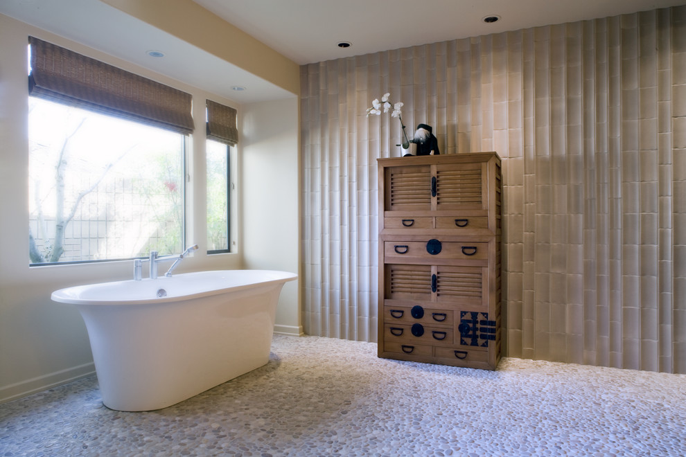 Photo of a transitional bathroom in Portland with a freestanding tub and pebble tile floors.