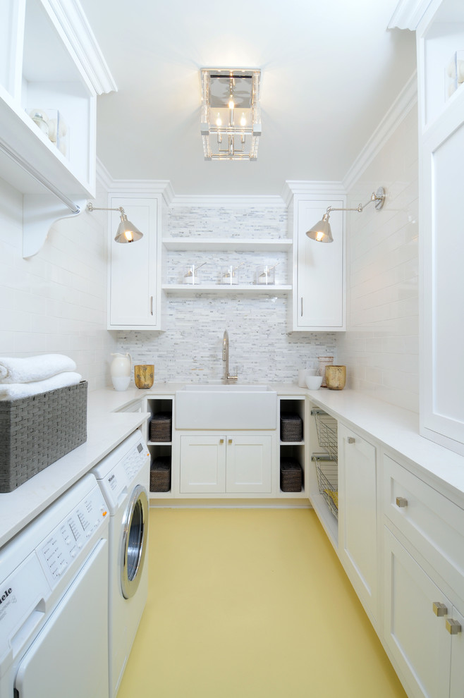 Photo of a mid-sized transitional u-shaped dedicated laundry room in Los Angeles with a farmhouse sink, shaker cabinets, white cabinets, white walls, a side-by-side washer and dryer, solid surface benchtops and painted wood floors.