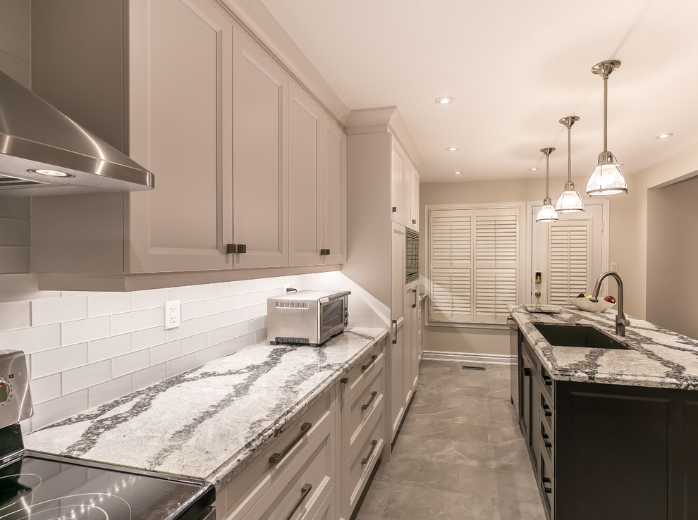 Inspiration for a large transitional gray floor enclosed kitchen remodel in Toronto with an undermount sink, recessed-panel cabinets, white cabinets, quartz countertops, white backsplash, ceramic backsplash, stainless steel appliances and an island