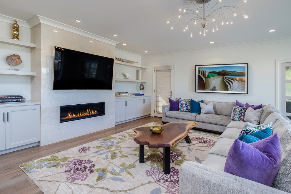 This is an example of a mediterranean family room in San Francisco with white walls, light hardwood floors, a ribbon fireplace and a wall-mounted tv.