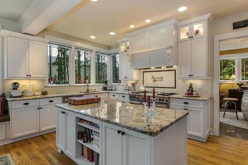 This is an example of an arts and crafts kitchen in Seattle with an undermount sink, white cabinets, granite benchtops, beige splashback, subway tile splashback, stainless steel appliances and medium hardwood floors.