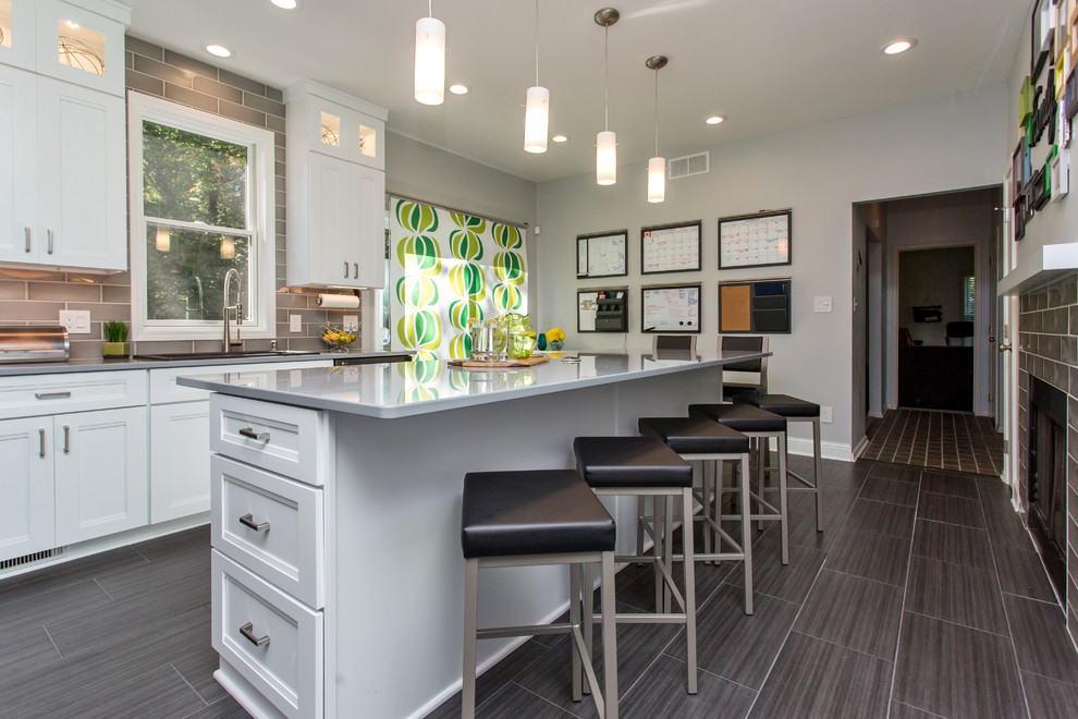 Mid-sized transitional u-shaped porcelain tile enclosed kitchen photo with a drop-in sink, recessed-panel cabinets, white cabinets, quartz countertops, gray backsplash, ceramic backsplash, stainless steel appliances and an island