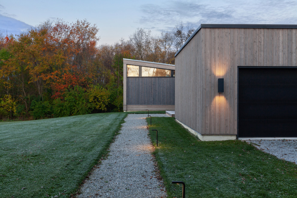 Foto på ett mellanstort funkis grått hus, med allt i ett plan, pulpettak och tak i metall