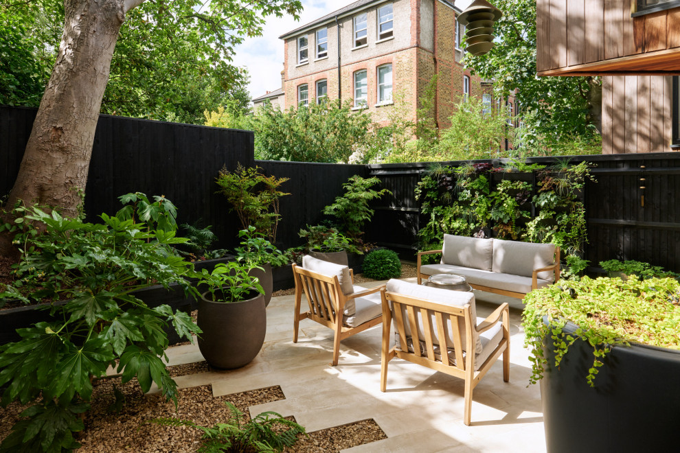 This is an example of a contemporary back patio in London with tiled flooring and no cover.