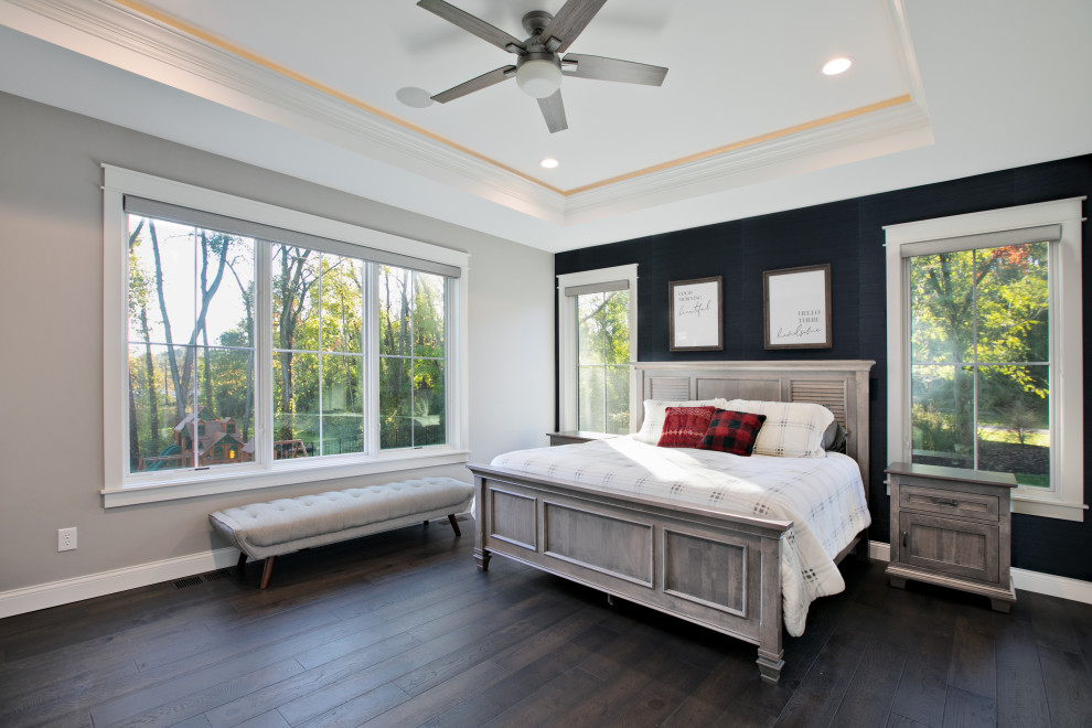 Large transitional master dark wood floor, brown floor, tray ceiling and wallpaper bedroom photo in Other with beige walls, a standard fireplace and a tile fireplace