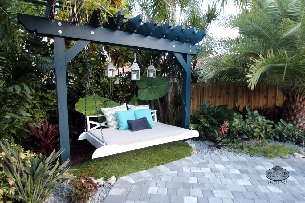 This is an example of a mid-sized tropical backyard patio in Miami with brick pavers.