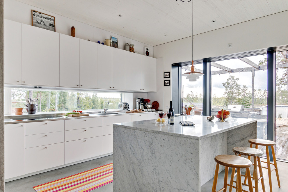 Design ideas for a scandinavian galley kitchen in Stockholm with an integrated sink, flat-panel cabinets, white cabinets, marble benchtops, window splashback, panelled appliances, concrete floors, with island and grey floor.
