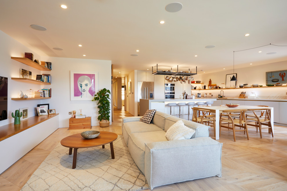 Inspiration for a medium sized contemporary open plan living room in London with white walls, no fireplace, a wall mounted tv, beige floors and light hardwood flooring.