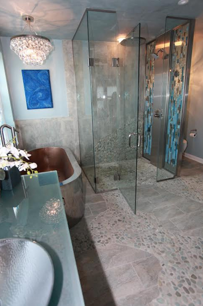 Photo of a large eclectic master bathroom in Philadelphia with flat-panel cabinets, dark wood cabinets, a freestanding tub, a curbless shower, a two-piece toilet, blue walls, pebble tile floors, a vessel sink, glass benchtops and a hinged shower door.
