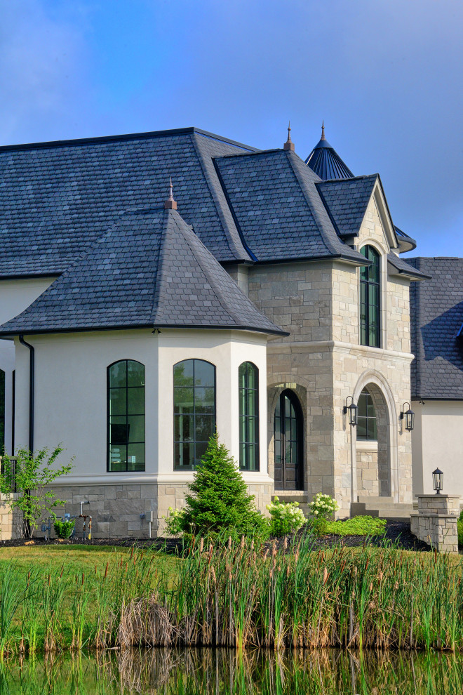 Idée de décoration pour une très grande façade de maison beige à deux étages et plus avec un revêtement mixte, un toit mixte et un toit gris.