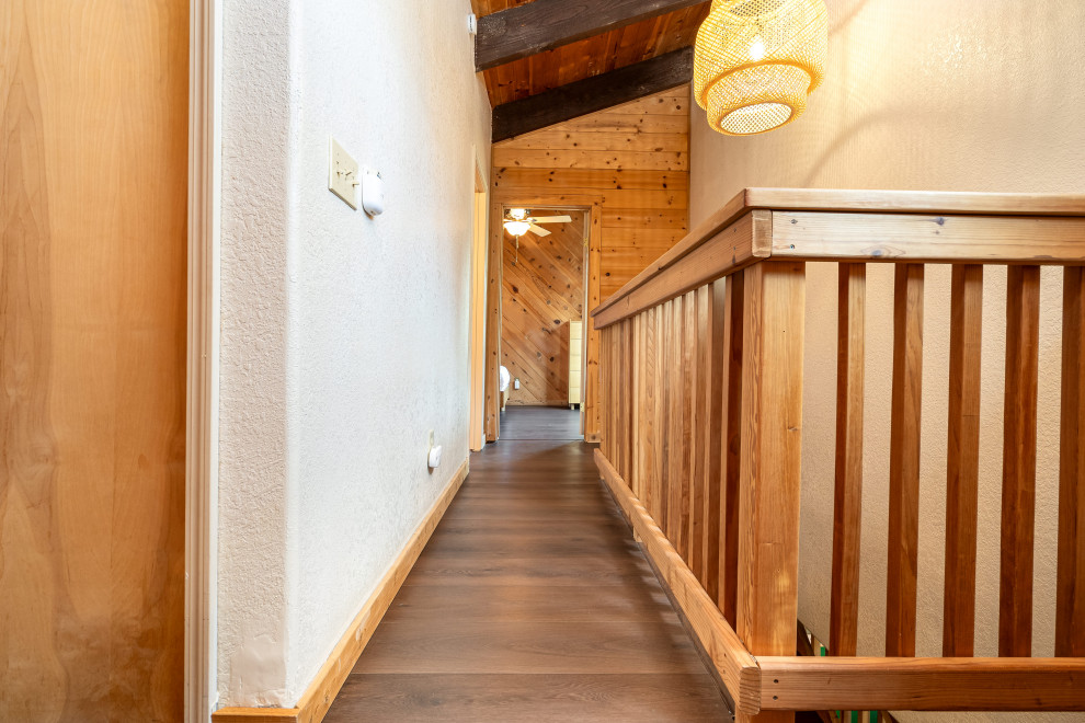 Cette photo montre un couloir éclectique de taille moyenne avec un mur marron, un sol en vinyl, un sol marron et poutres apparentes.