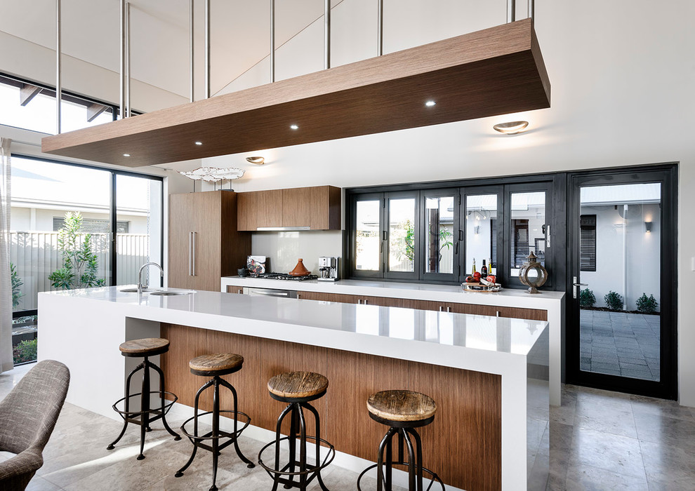Large contemporary galley eat-in kitchen in Perth with medium wood cabinets, quartz benchtops, glass sheet splashback, travertine floors, with island, a double-bowl sink, flat-panel cabinets, grey splashback and stainless steel appliances.