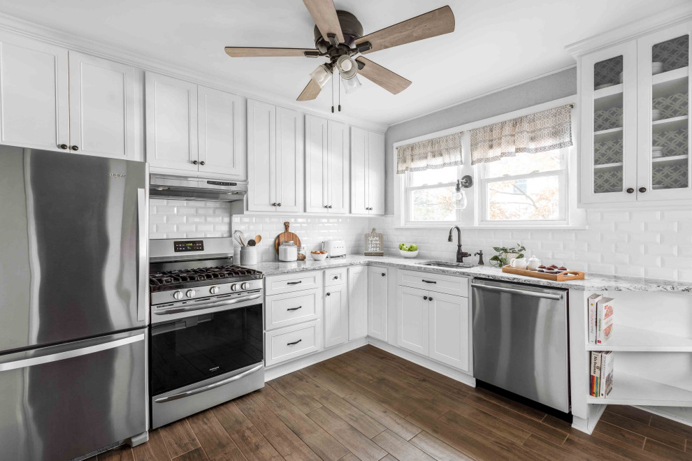 Mid-sized cottage l-shaped porcelain tile and brown floor eat-in kitchen photo in Philadelphia with a single-bowl sink, flat-panel cabinets, white cabinets, quartzite countertops, white backsplash, ceramic backsplash, stainless steel appliances and gray countertops