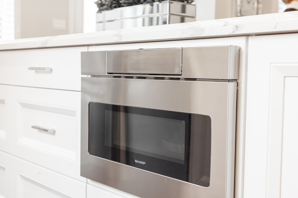 Enclosed kitchen - large transitional l-shaped medium tone wood floor and brown floor enclosed kitchen idea with an undermount sink, recessed-panel cabinets, white cabinets, quartz countertops, gray backsplash, ceramic backsplash, stainless steel appliances, an island and white countertops