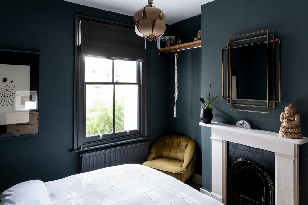 Ispirazione per una camera degli ospiti contemporanea con pareti blu, pavimento in legno massello medio e camino classico
