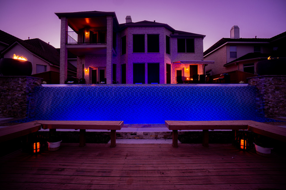 Large contemporary back rectangular infinity swimming pool in Houston with decking.