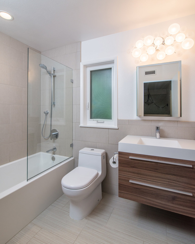 Small modern bathroom in San Diego with an integrated sink, flat-panel cabinets, dark wood cabinets, solid surface benchtops, an alcove tub, a shower/bathtub combo, a one-piece toilet, beige tile, ceramic tile, white walls and ceramic floors.