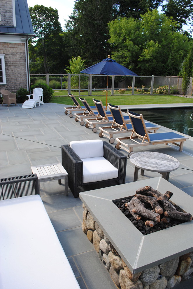 Photo of a mid-sized transitional backyard rectangular pool in Boston with natural stone pavers.