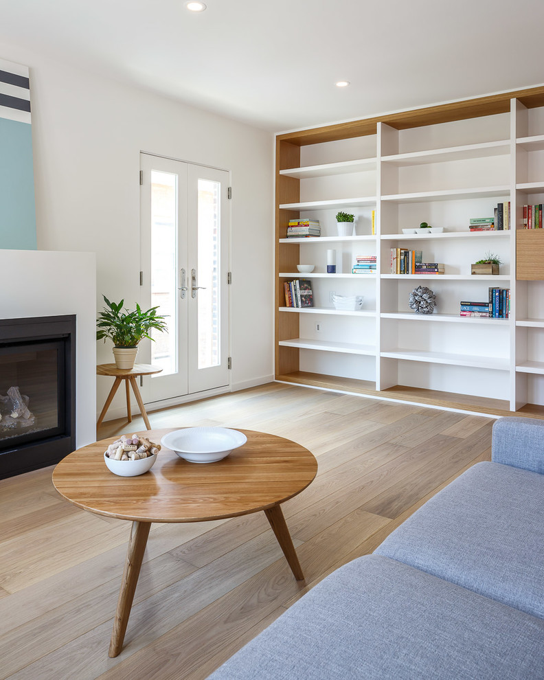 This is an example of a mid-sized modern open concept living room in Ottawa with white walls, light hardwood floors, a standard fireplace, a plaster fireplace surround and beige floor.