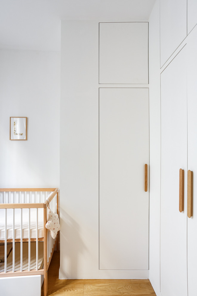 Imagen de habitación de bebé contemporánea con paredes blancas, suelo de madera oscura y suelo marrón