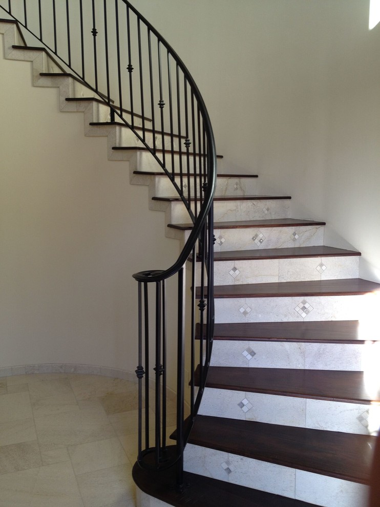 Mid-sized mediterranean wood curved staircase in San Luis Obispo with tile risers and metal railing.