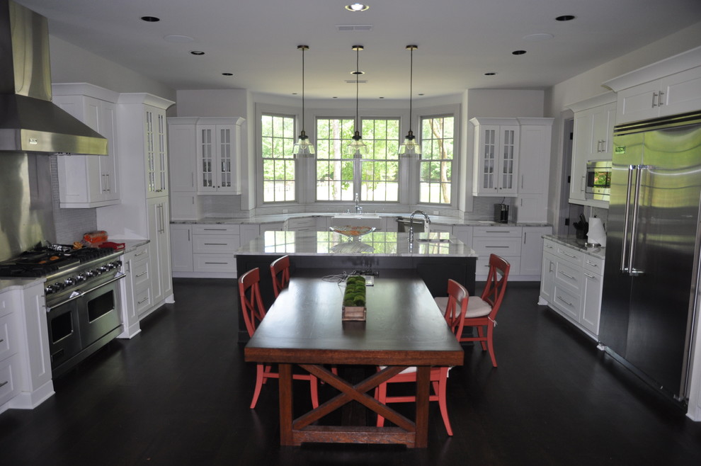 Example of a mid-sized transitional u-shaped dark wood floor and brown floor enclosed kitchen design with an undermount sink, shaker cabinets, white cabinets, window backsplash, stainless steel appliances and an island