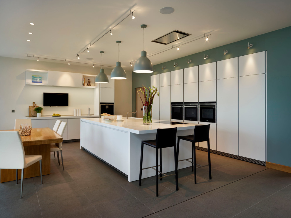 Design ideas for a contemporary l-shaped eat-in kitchen in Devon with flat-panel cabinets, white cabinets, black appliances and with island.