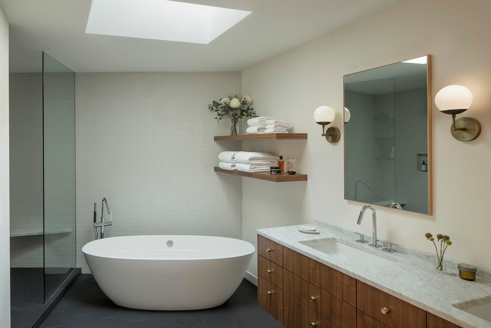 This is an example of a mid-sized midcentury master bathroom in Portland with flat-panel cabinets, dark wood cabinets, a freestanding tub, an alcove shower, white tile, subway tile, white walls, slate floors, an undermount sink, marble benchtops, grey floor, a hinged shower door and grey benchtops.