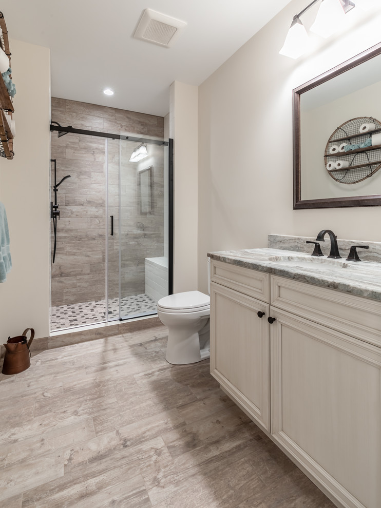 Design ideas for a mid-sized transitional 3/4 bathroom in DC Metro with recessed-panel cabinets, beige cabinets, a two-piece toilet, porcelain tile, beige walls, porcelain floors, an undermount sink, engineered quartz benchtops, an alcove shower, beige tile, beige floor, a sliding shower screen and grey benchtops.