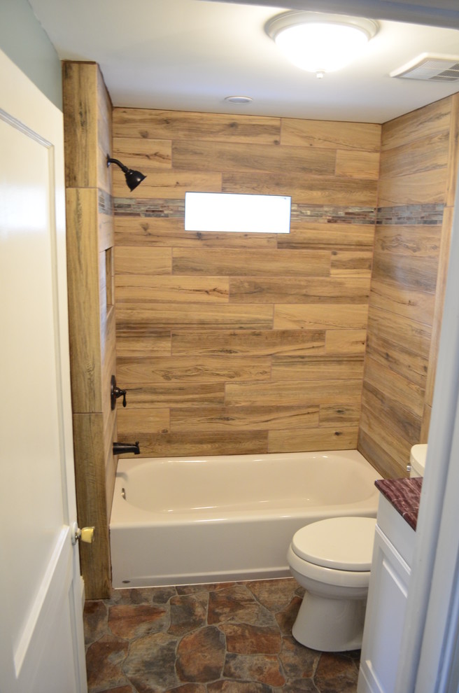 Photo of a mid-sized country kids bathroom in Philadelphia with recessed-panel cabinets, white cabinets, an alcove tub, a two-piece toilet, brown tile, porcelain tile, green walls, vinyl floors, an undermount sink and marble benchtops.