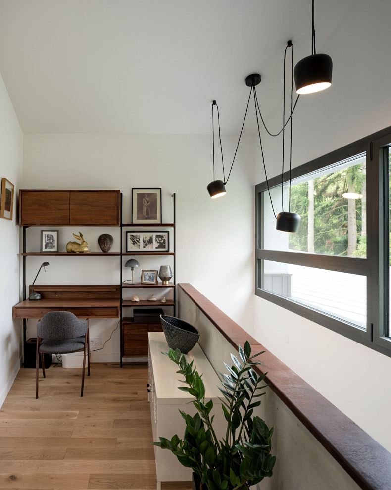 Modelo de despacho blanco contemporáneo pequeño sin chimenea con paredes blancas, suelo de madera clara, escritorio empotrado y suelo beige
