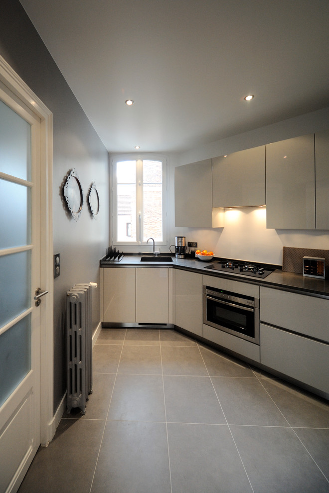 Photo of a mid-sized contemporary l-shaped separate kitchen in Paris with white cabinets and no island.